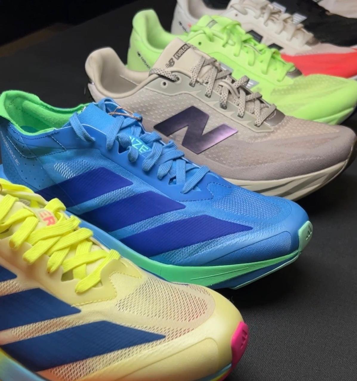 Vários tênis de corrida de performance alinhados, incluindo Adidas Adizero Drive RC e New Balance FuelCell Rebel v5